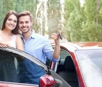 A smiling couple stands beside their car, holding the keys — a visual celebration of car ownership made possible through accessible car finance options.