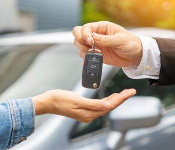Handing over car keys to a buyer, symbolizing approval and eligibility criteria for car loan financing.