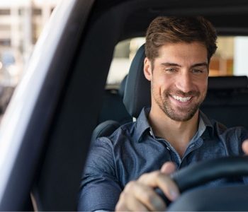 Smiling man driving a car with all-inclusive payments covering vehicle costs