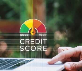 Person checking financial data on a laptop with a gauge illustrating ways to improve credit score